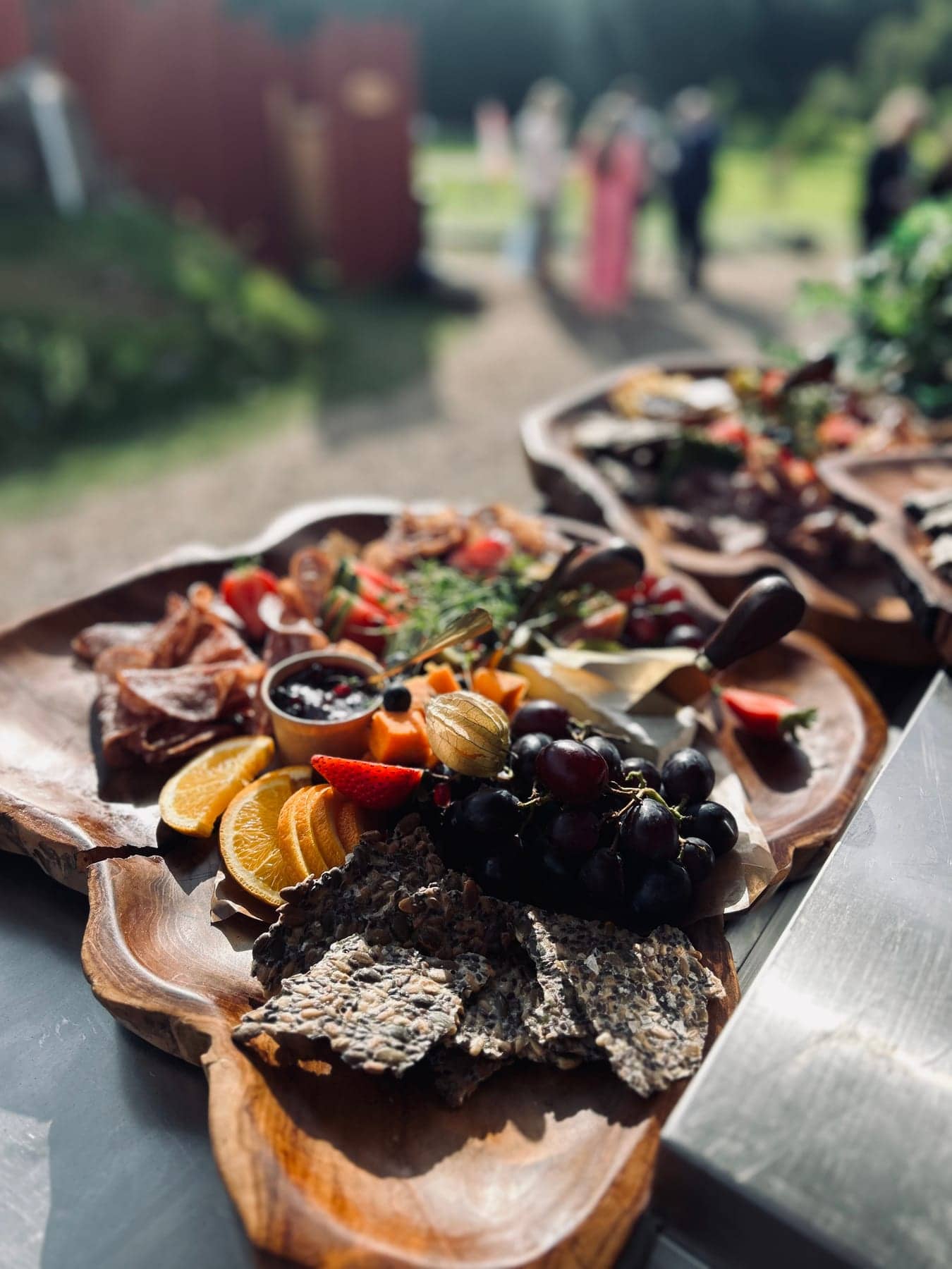 Chark, ost, frukt och fröknäcke på ett träfat utomhus